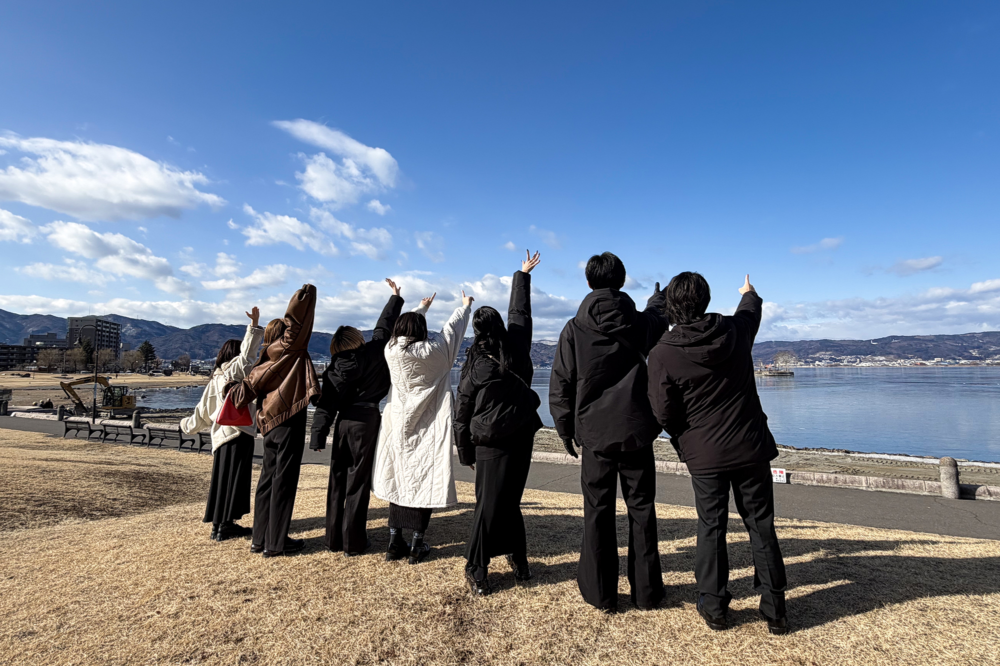 諏訪湖を前に並ぶムゲングループスタッフ
